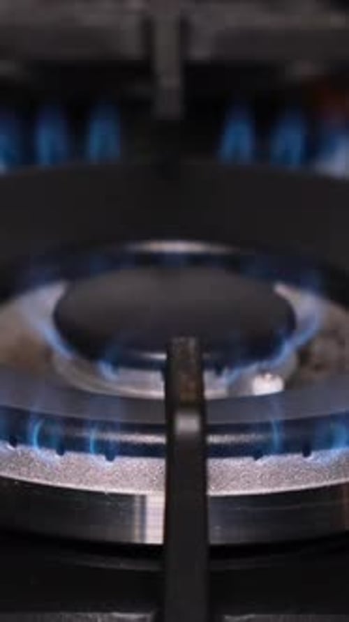 A Closeup of the Ignition of a Gas Stove Gas Burns with a Blue Flame in a Dark Room Vertical Video
