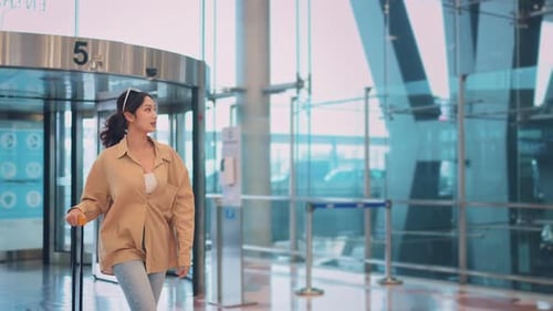 Happiness smiling asian woman passenger walking with a yellow suitcase luggage at airport terminal