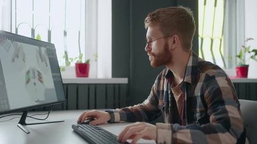Hübscher bärtiger 3D-Modellierer, der ein Motorprojekt für Auto oder Flugzeug im modernen Büro erstellt