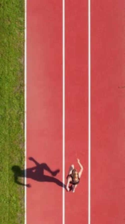 Top View Of Young Woman Running On Red Athletic Track At Stadium