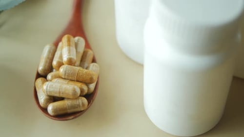 Herbal Capsule Supplement on a Wooden Spoon