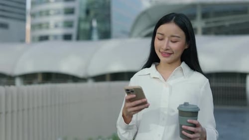 Awesome Girl Manager After Work Going Home Using Smartphone and Holding Coffee