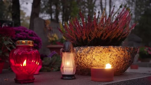 Grave Candles Lights Glowing on Cemetery at Night on All Saints Day