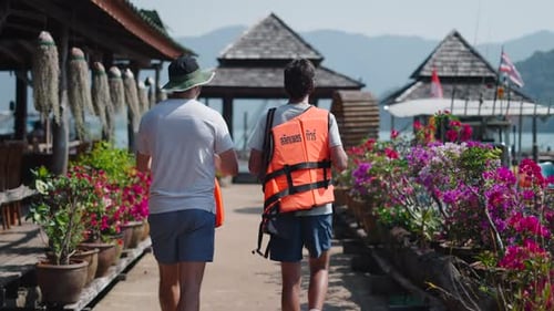 Two Guys in Life Jackets Walk to the Dock Before Kayaking