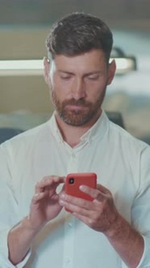 Man Looking at Cellphone and Cheering in Office