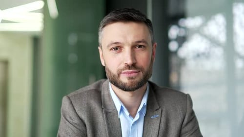 Portrait of happy businessman sitting at workplace in a business office. Confident successful