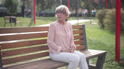 Woman Sitting on Park Bench Looking at Watch