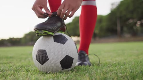 Video of biracial football player with ball tie the laces