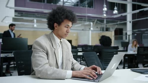 African American Man Preparing Annual Financial Report in Modern Office Space