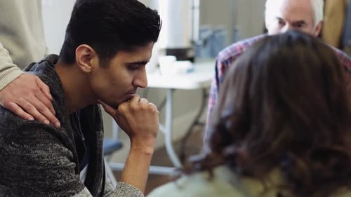 Young man sits with support group indoors