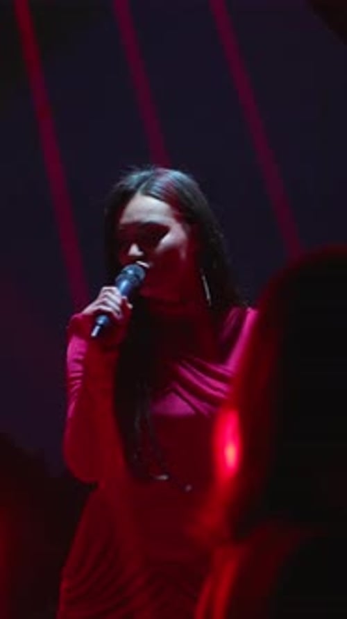 Young Woman Singing on Stage with Neon Lighting