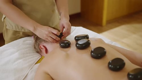 Asian Spa Wellness Center Masseuse Makes Hot Stones Massage to Client Back and Neck Woman Performs