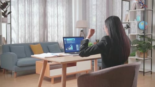 Woman Working on Laptop Celebrating Success at Home