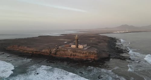 Experience the stunning coastal vista from above, as the majestic ocean meets a towering lighthouse—