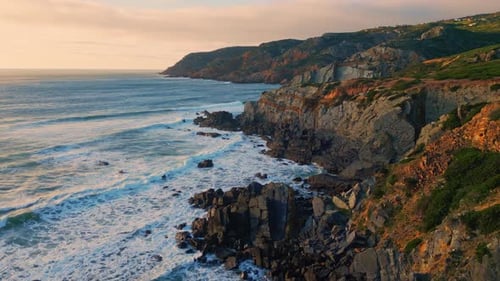 Aerial view of stormy sea waves splashing on picturesque rocky coastline
