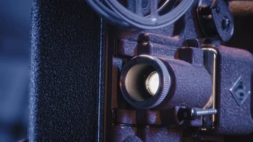 Old Film Projector with Glowing Lens in Dim Light