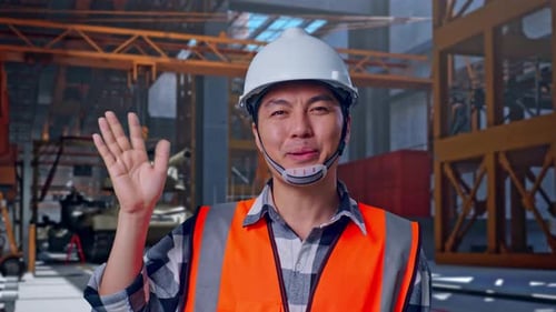 Asian Male Engineer Smiling To Camera And Waving Hand Saying Bye, Tank Under Construction