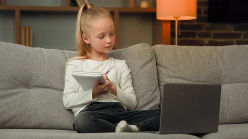Child Writes in Notebook, Waves at Laptop