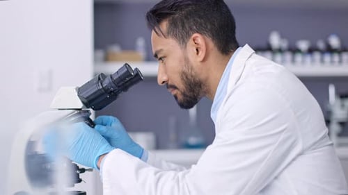 Man Looks Through Microscope in Modern Lab