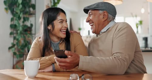 Grandfather and Granddaughter Laughing and Looking at Phone
