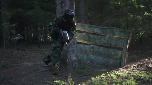 Hauptspieler im Paintball-Spiel mit Waffe, die auf dem Schießstand in Zeitlupe läuft. Paintball-Team Attac...
