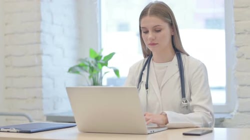Female Doctor Working on Laptop in Bright Office