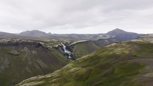Aerial view of waterfall in rugged valley, Iceland.