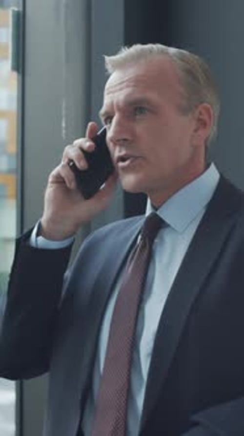 Businessman Talking on Mobile Phone near Office Window