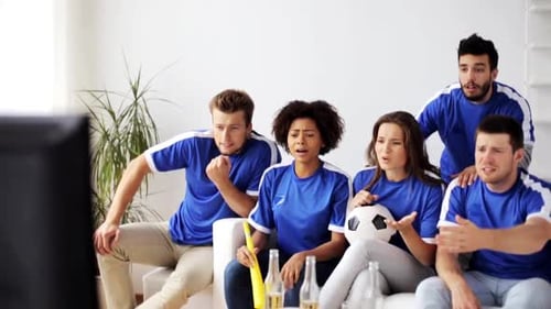 Multiethnic friends watch a soccer game on tv at home disappointed by the loss