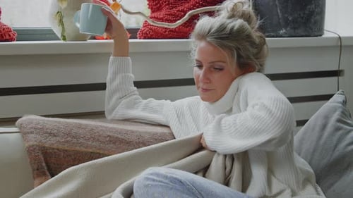 Woman Lounging on Couch Drinking from Blue Mug