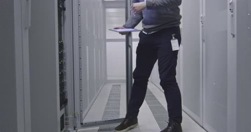 Ingénieur informatique ou spécialiste de la science des données travaillant sur une tablette dans une salle de serveurs dans un cloud moderne
