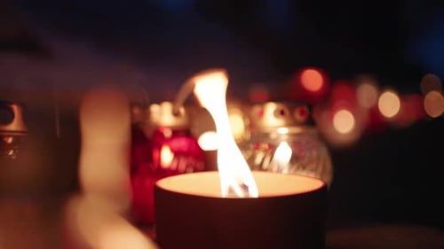 Grave Candles Lights Glowing on Cemetery at Night on All Saints Day