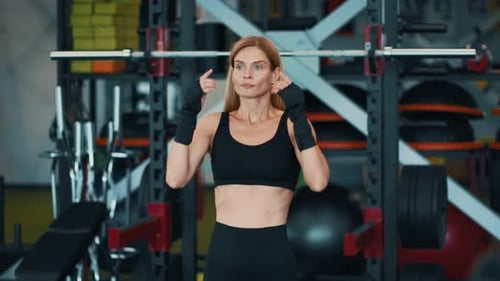Woman Preparing for Strength Training in a Modern Gym Setting