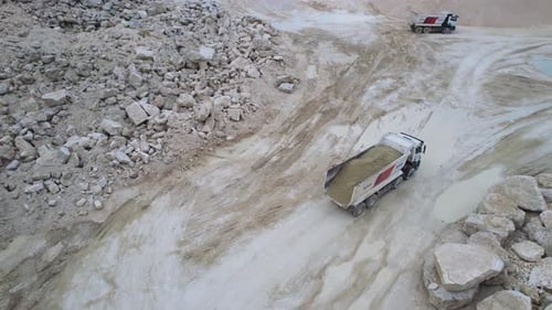 Drohnenaufnahme großer Muldenkipper, die auf einer Sandsteingrube fahren, Blick von oben auf Fahrzeuge, Industrieplatz