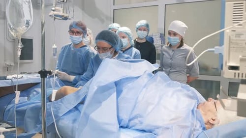 Ein Arzt und Assistenten operieren eine alte Studentin bei chirurgischer Operation