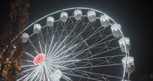 Illuminated Ferris Wheel Turning at Night