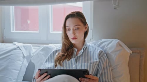 Woman Using Tablet in Bed at Home