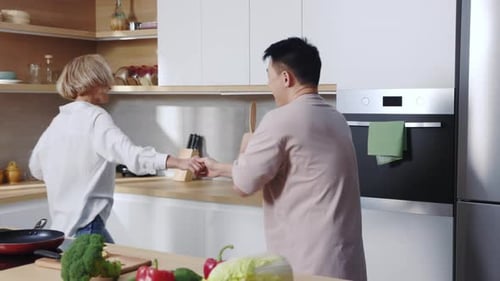Couple singing with wooden spoons in modern kitchen