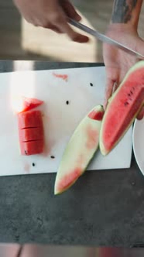 Chef Slices Watermelon Into Small Triangles on a White Cutting Board