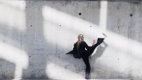 Barefoot Woman Dancing Against Concrete Wall