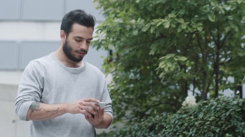 Young Man Using Mobile Phone Outside in Urban Setting