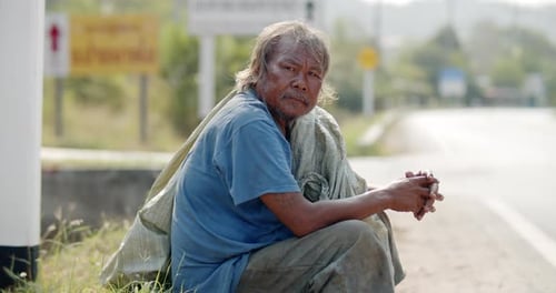 An Asian man who is a poor ragpicker or collects garbage and sells, sitting on the side of the road