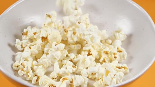 Jeter du pop-corn salé dans un bol en céramique. Tourné avec une caméra haute vitesse. Snack au Ralenti