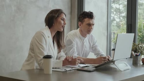 Two Professionals Discussing Data Analysis on a Laptop