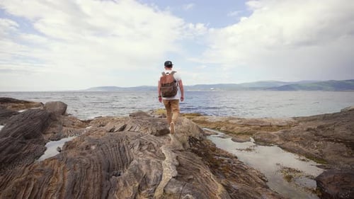 Amidst the Wild Nature of Norway a Lone Hiker Carrying a Backpack is Captured Wandering Along a