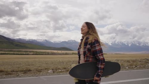 Young Woman Walking on Road with Skateboard