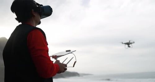 Man wearing VR headset flying drone near beach