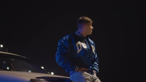 Caucasian Man Leaning on Car Hood Under Neon Bridge Lights Wearing Blue Bomber Jacket Contemplative