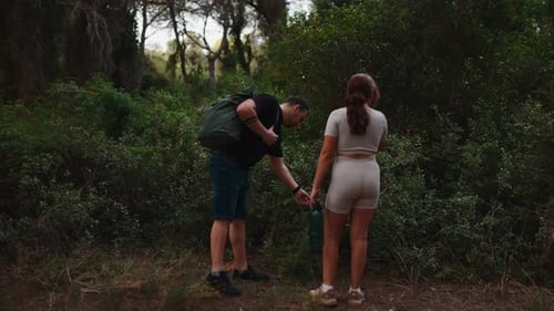 Young Couple Hiking and Talking in a Green Forest