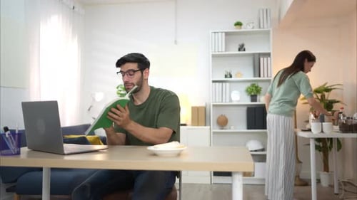 Man With Laptop Talking While Woman Makes Coffee